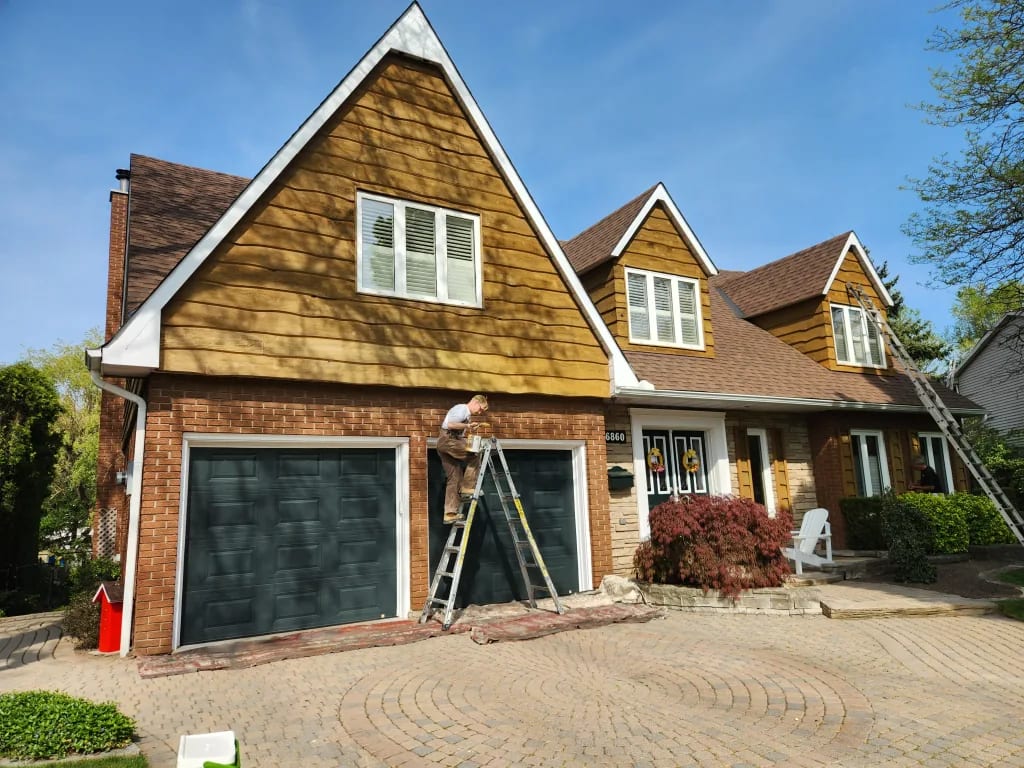 Exterior painting by Sigma Painting — wood shingle siding being refinished above a brick facade