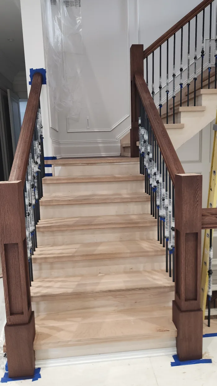 Stair staining by Sigma Painting — stained handrail and newel posts with black spindles individually masked