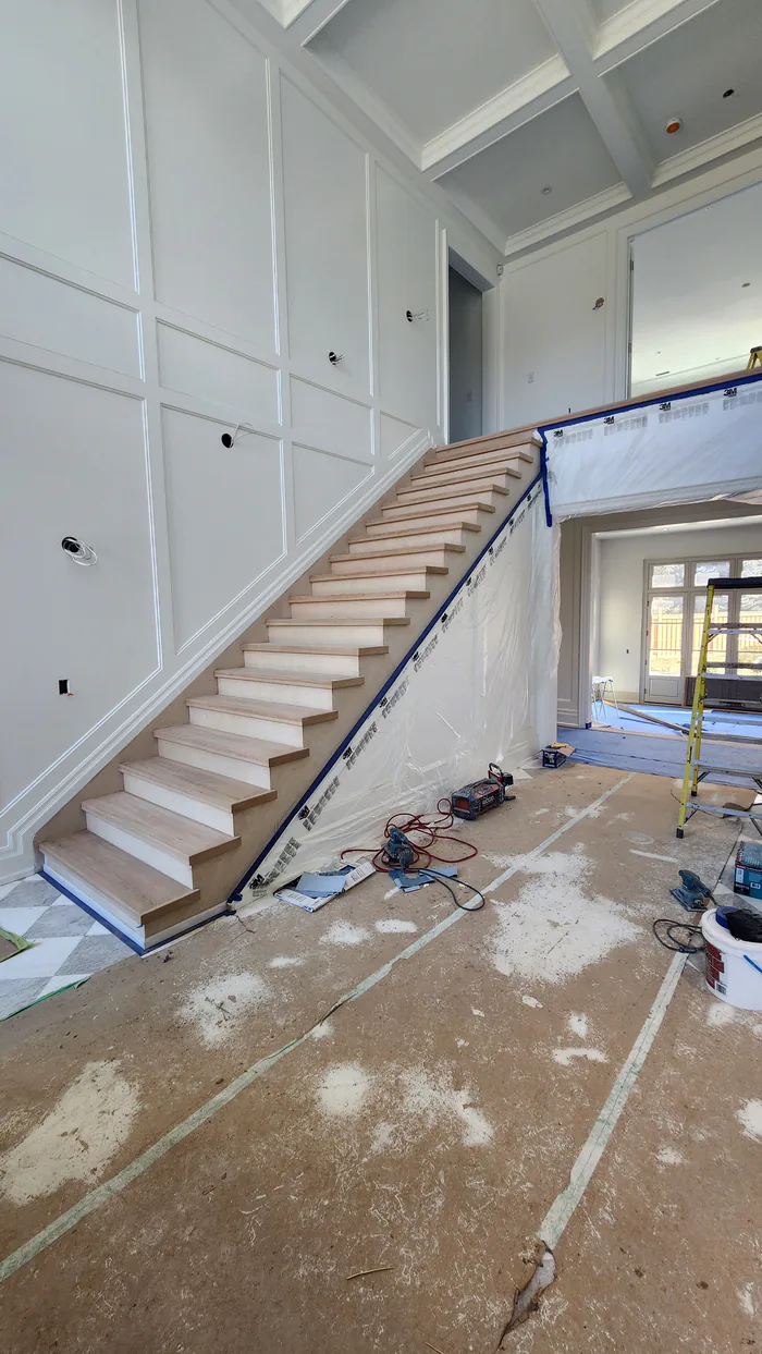 Stair preparation by Sigma Painting — bare wood treads beside white wall panelling with surrounding surfaces protected