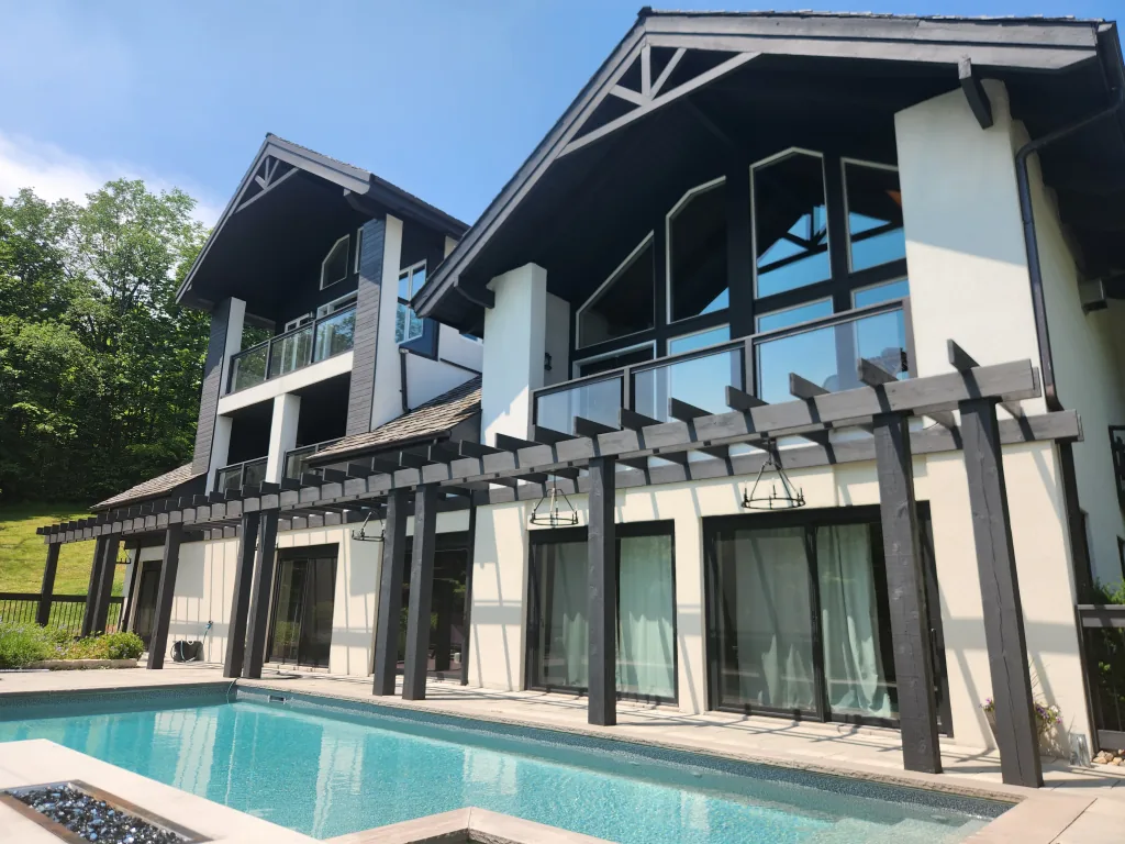 Exterior painting by Sigma Painting — chalet-style home with dark-stained timber and pergola beside the pool