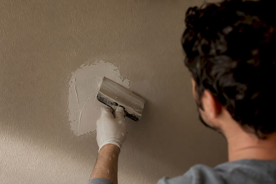Hand pressing joint compound through mesh drywall patch